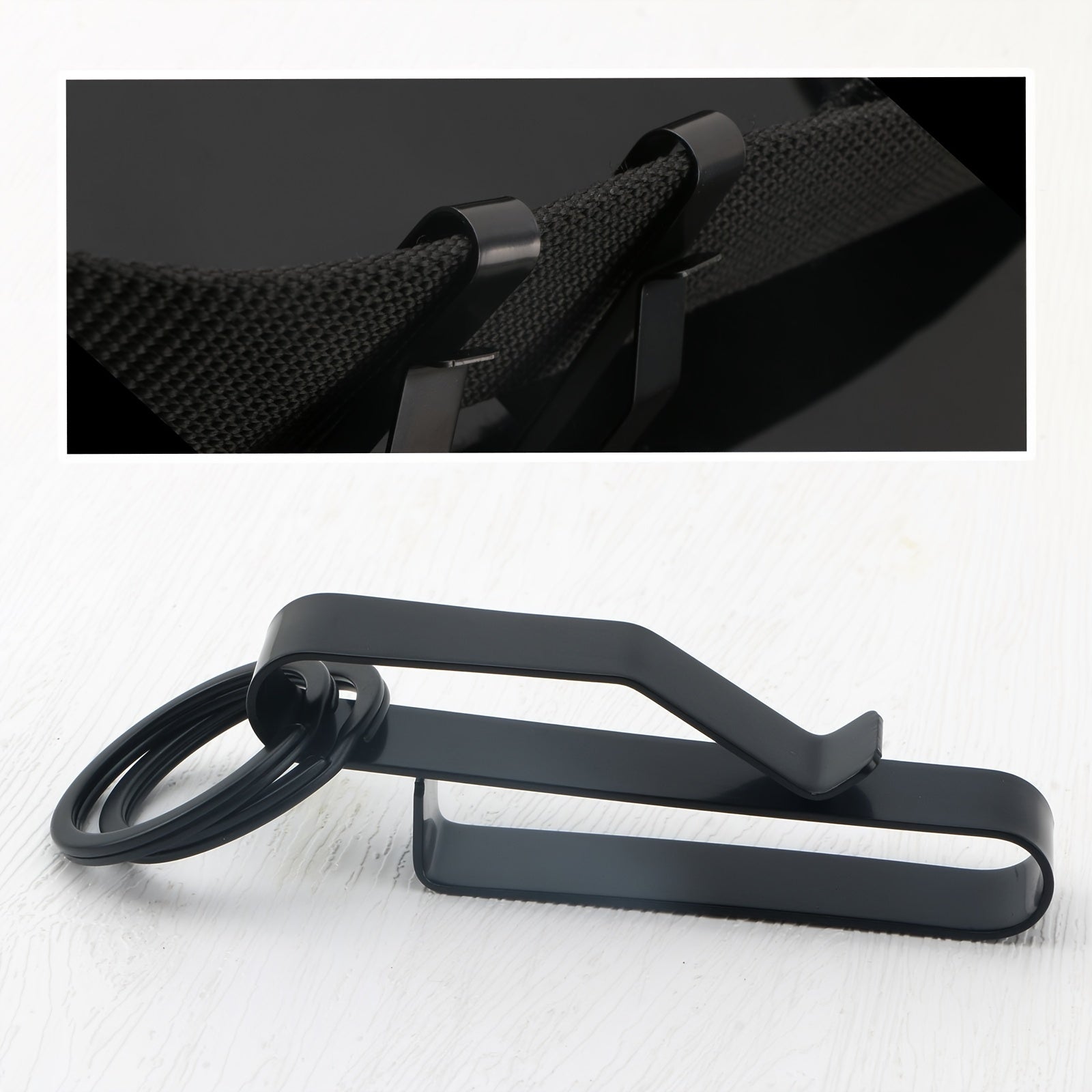 Black metal clip with ring on white background, inset of clip on textured surface.