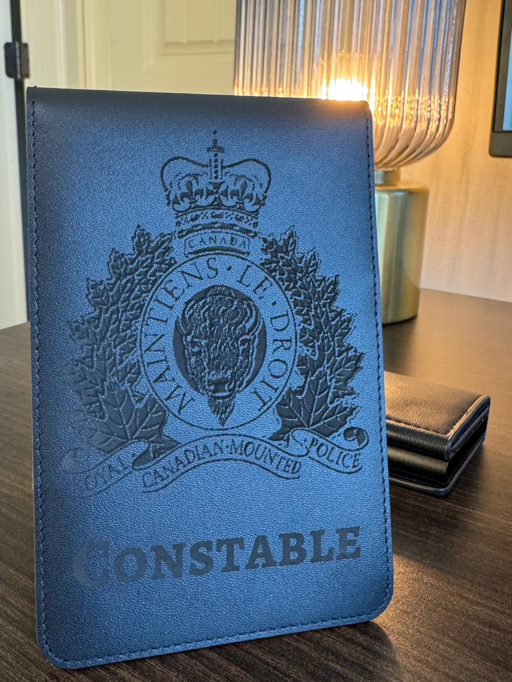 Blue leather cover with RCMP Constable emblem on a wooden surface