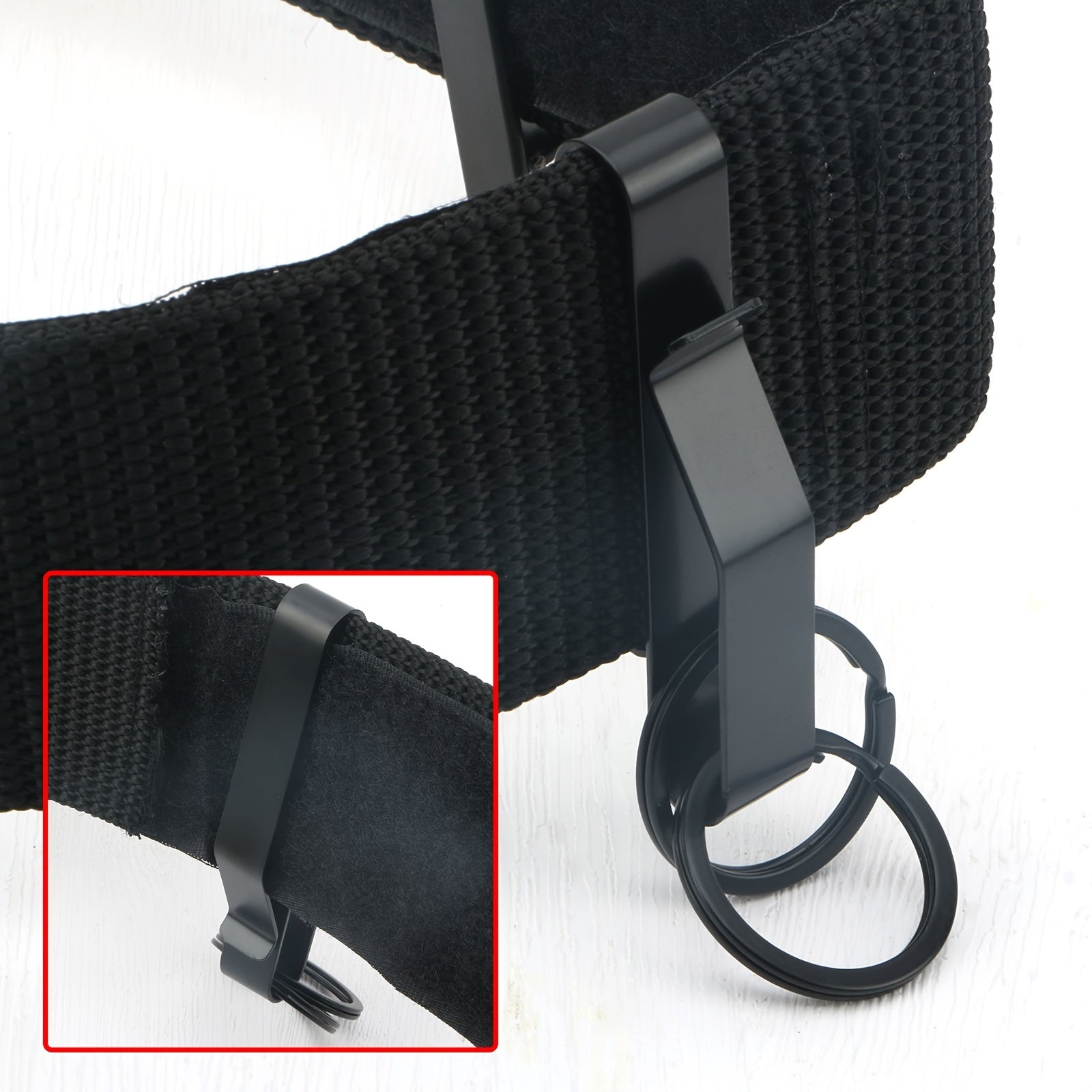 Close-up of a black strap with a metal clip on a white background.