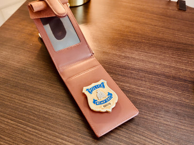 Brown leather wallet with a police badge emblem on a wooden surface
