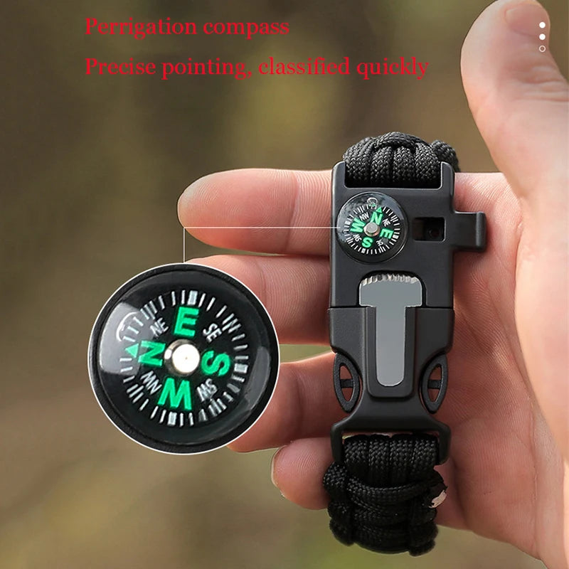 Hand holding a compass with paracord, against a blurred natural background